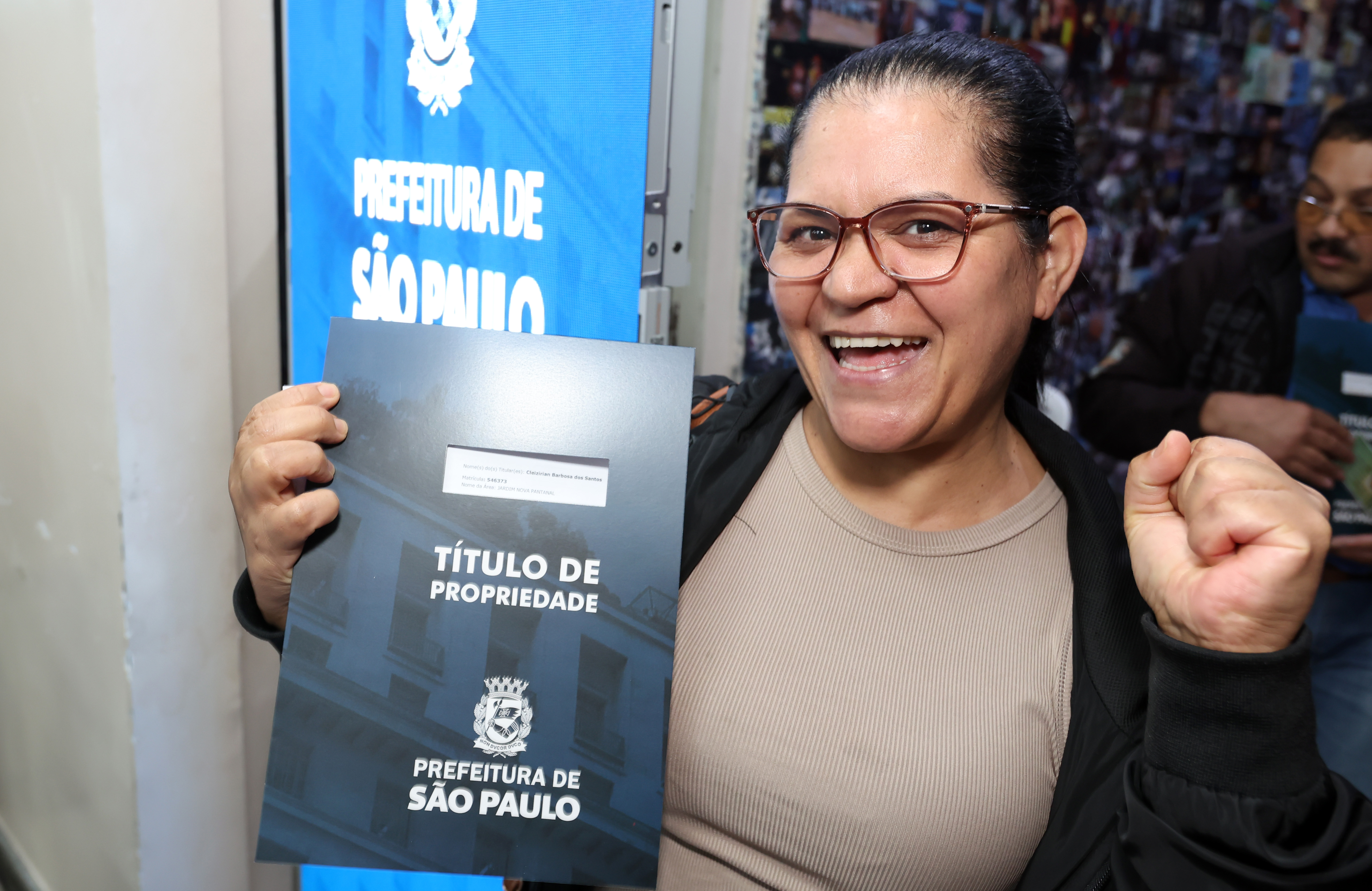 Mulher recebe o título de propriedade de seu imóvel