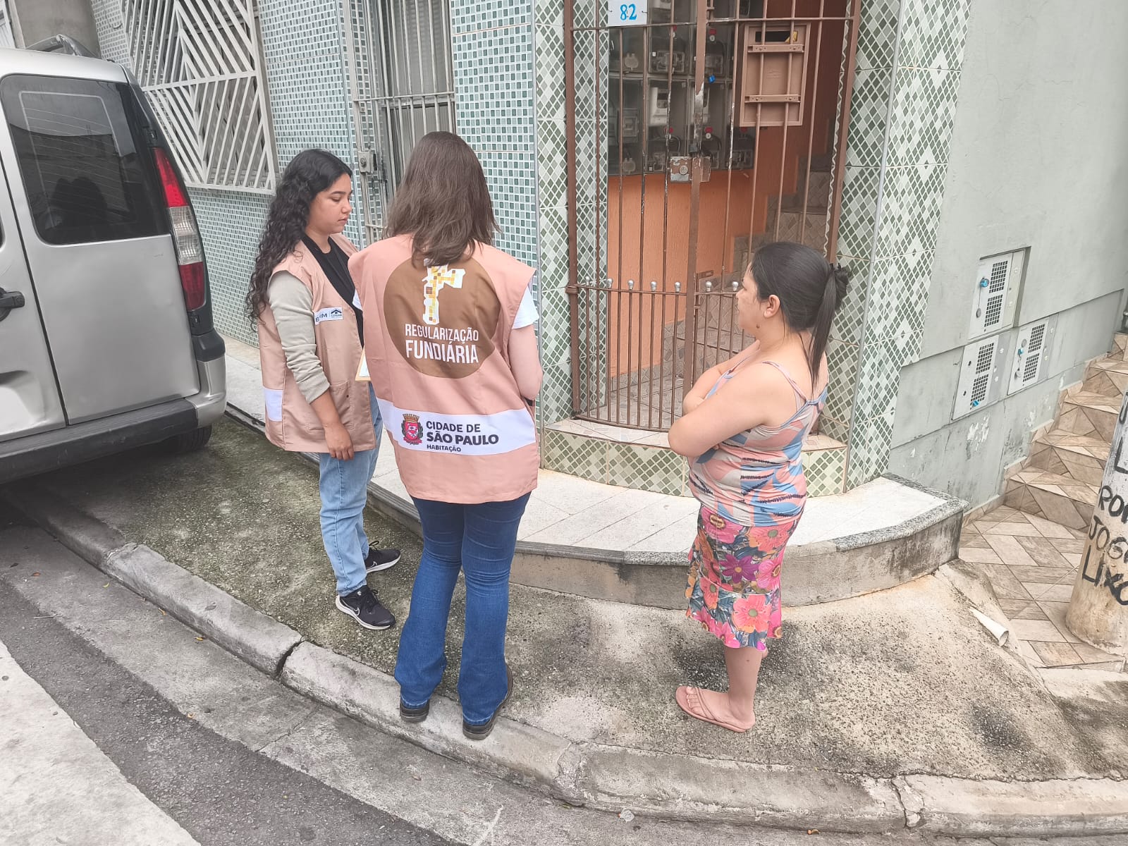 Duas pessoas da equipe de Regularização Fundiária conversando com uma moradora 