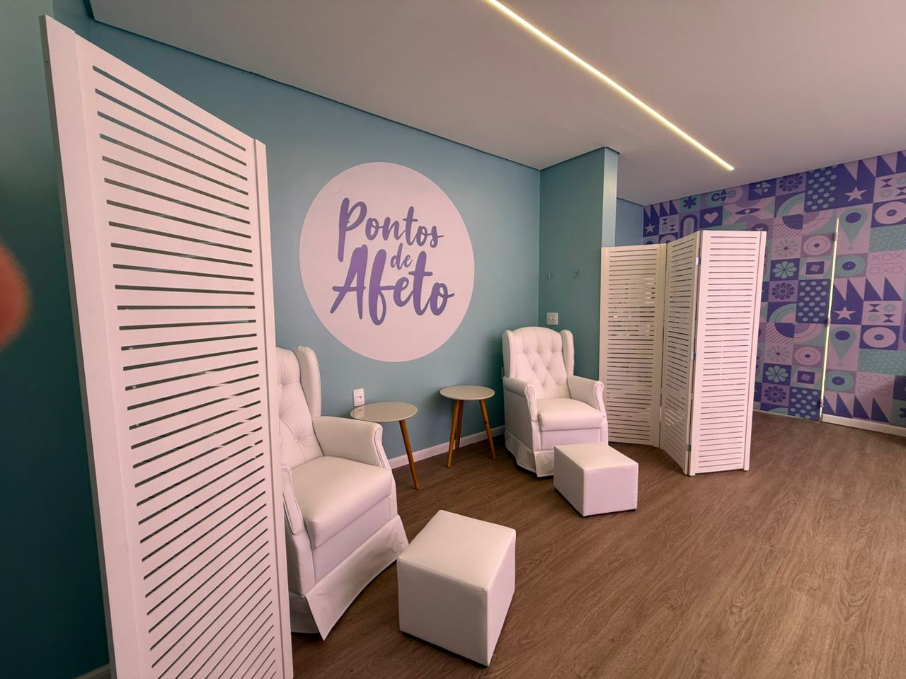 sala em tom lilás com duas poltronas branca, apoio de pé, bimbo branco. Logo Pontos de Afeto