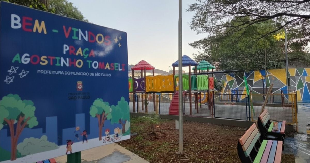 em primeiro plano, há uma grande placa azul de boas-vindas. Em letras grandes e coloridas, ela diz: