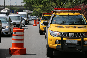 Viaturas da CET, cones laranja e carros trafegando em via ao lado.